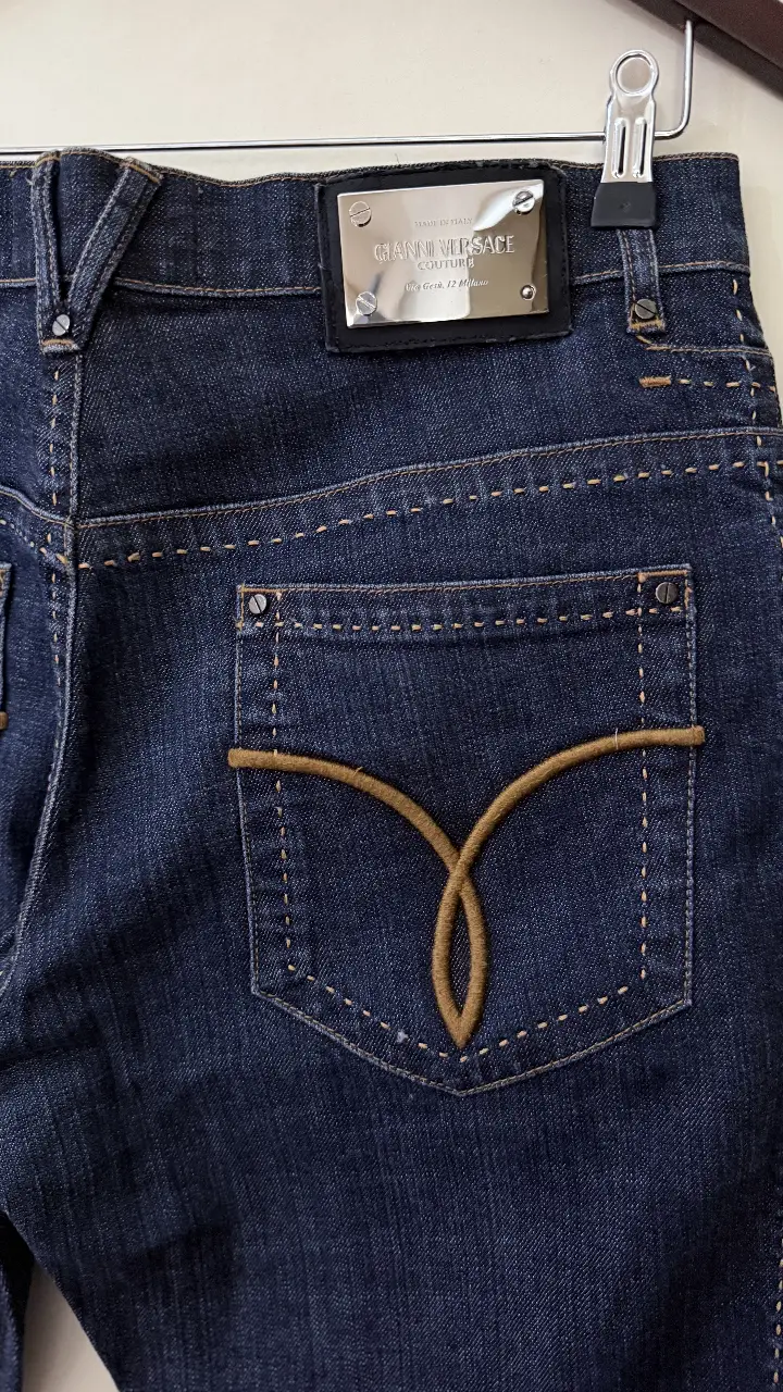 Jeans recto de hombre, azul oscuro, con detalle de logo en bolsillo trasero y etiqueta de marca en la cintura. Un clásico de la moda.
