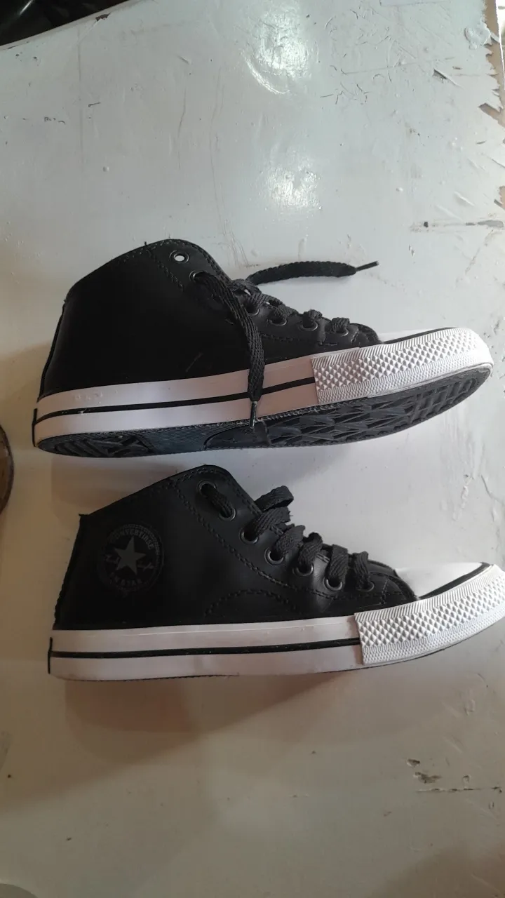 Zapatillas Converse negras de caña media, con puntera blanca y suela de goma. Diseño clásico con el logo de la marca en el lateral y en la lengüeta. Ideales para un look casual y urbano.