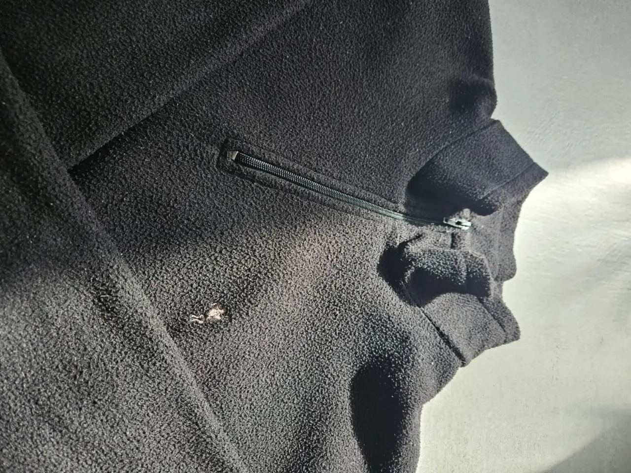Buzo polar negro con cierre y bolsillo en el pecho. Ideal para el invierno, cómodo y abrigado.