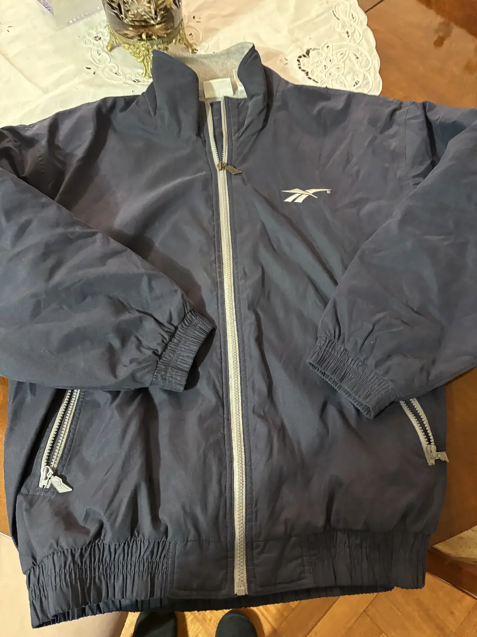 Campera deportiva Reebok azul marino para hombre. Con cierre frontal, bolsillos con cierre y logo bordado. Interior de polar gris. Talle L.Reversible!! 