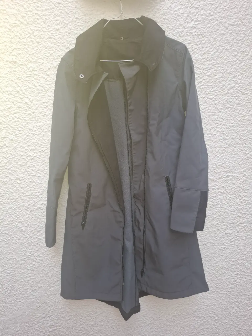 Trench gris oscuro con cuello negro y cierre frontal. Ideal para lluvia y días frescos. Un clásico atemporal para tu guardarropa.