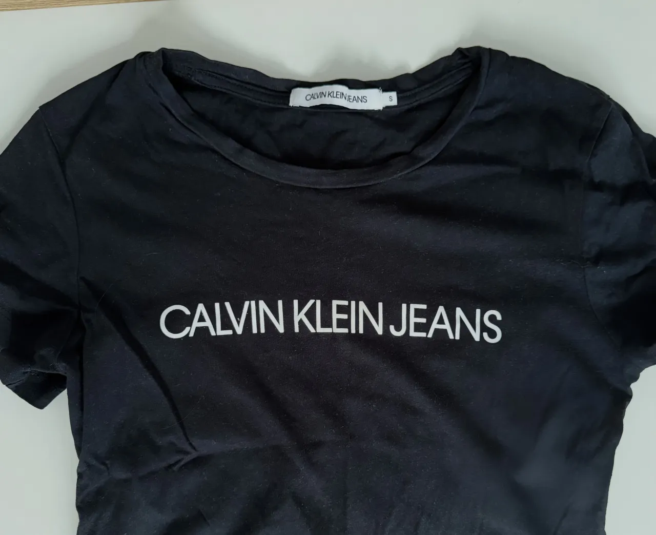 Remera negra de manga corta con logo de Calvin Klein Jeans estampado en blanco en el frente.