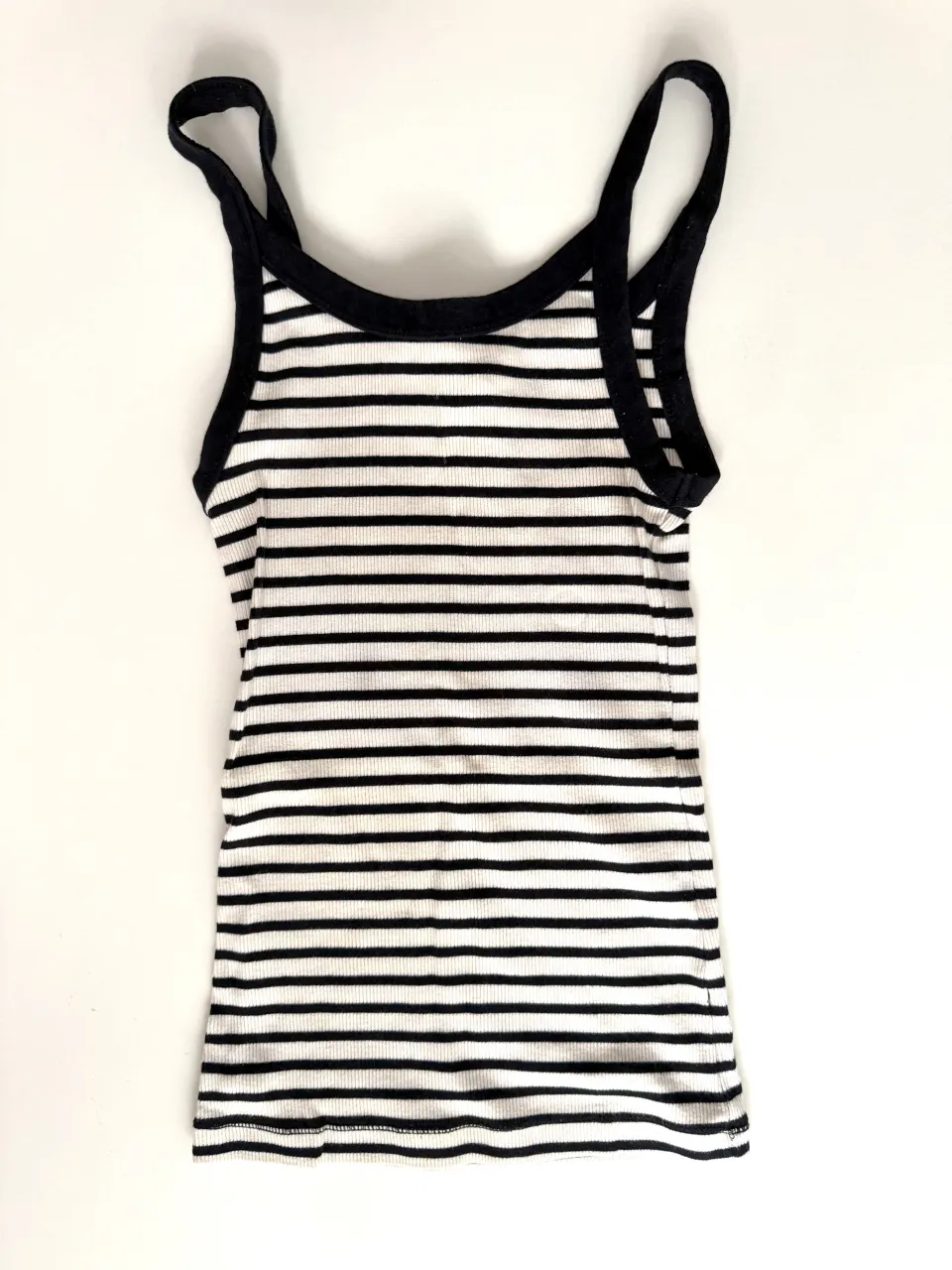 Musculosa a rayas finas blancas y azul oscuro. Tiene breteles finos y cuello redondo con borde negro.