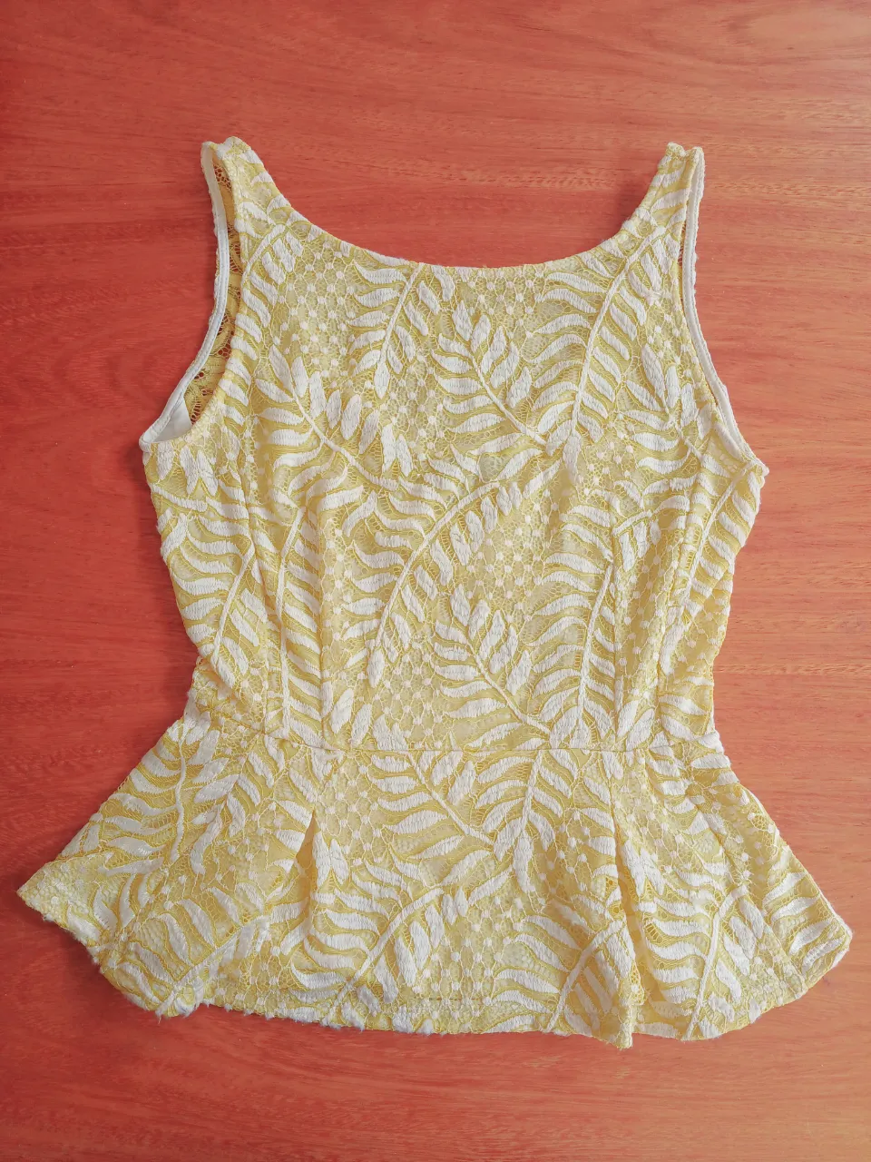 Musculosa amarilla  de encaje elastizado amarillo pastel forrada en tela elastizada blanca. Posee un corte peplum en la cintura.