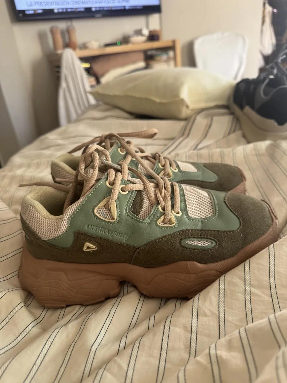 Zapatillas deportivas urbanas con un diseño moderno y cómodo. Ideales para el día a día o para complementar un look casual y canchero. Combinan tonos verdes y marrones, con detalles en beige y cordones a tono. Perfectas para quienes buscan estilo y confort en su calzado.