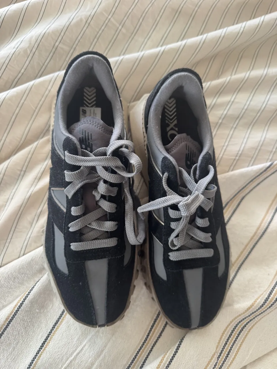 Zapatillas deportivas New Balance XC-72 negras y grises, ideales para running o uso casual. Diseño moderno y cómodo.