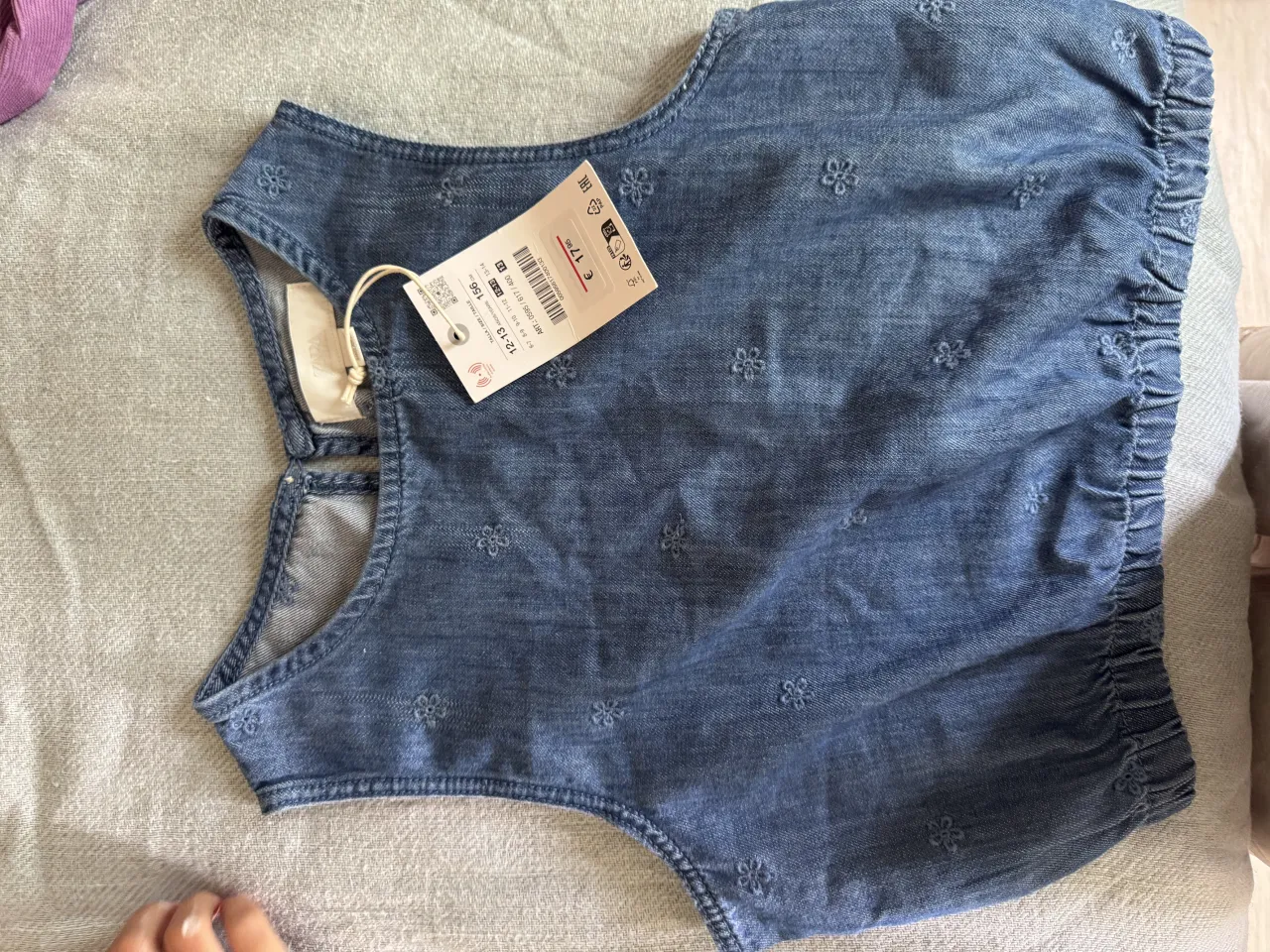 Remera de jean con delicados bordados de flores. Diseño sin mangas y con detalles elásticos en los laterales para un ajuste cómodo. Ideal para un look casual y fresco.