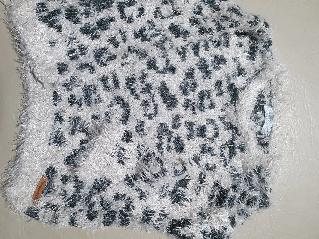 Sweater de tejido peludo con estampado de leopardo en tonos grises y blancos. Ideal para un look casual y abrigado.