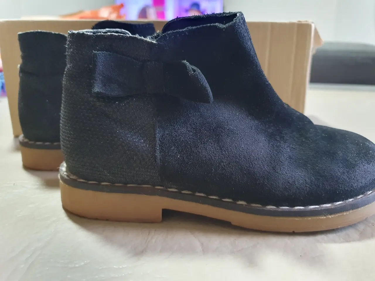 Botines negros para niña, con detalle de moño y cierre lateral. Suela marrón claro.