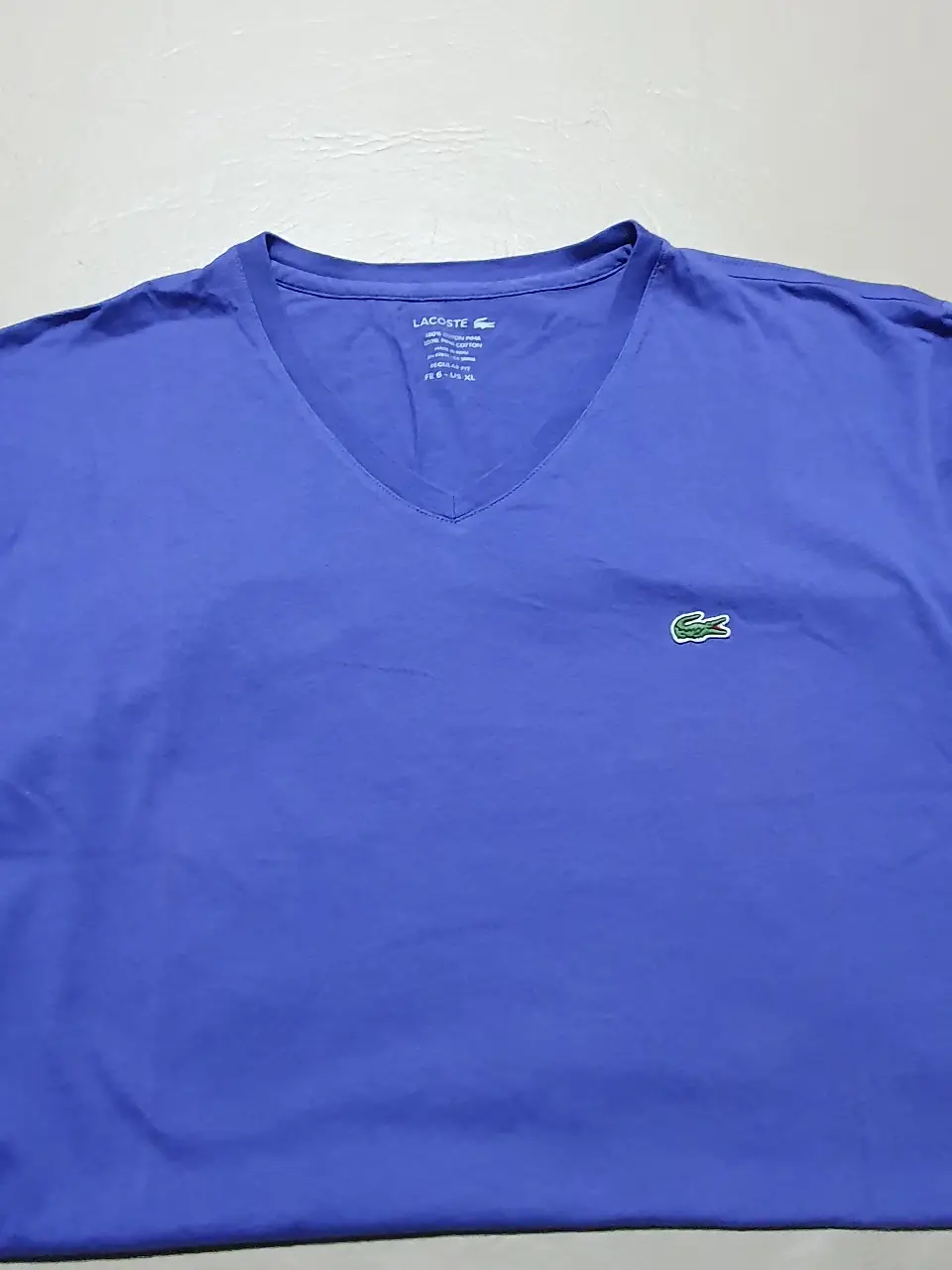 Remera Lacoste azul, de algodón pima, con cuello en V y el logo del cocodrilo bordado. Talle XL, corte regular fit, ideal para un look casual y cómodo.