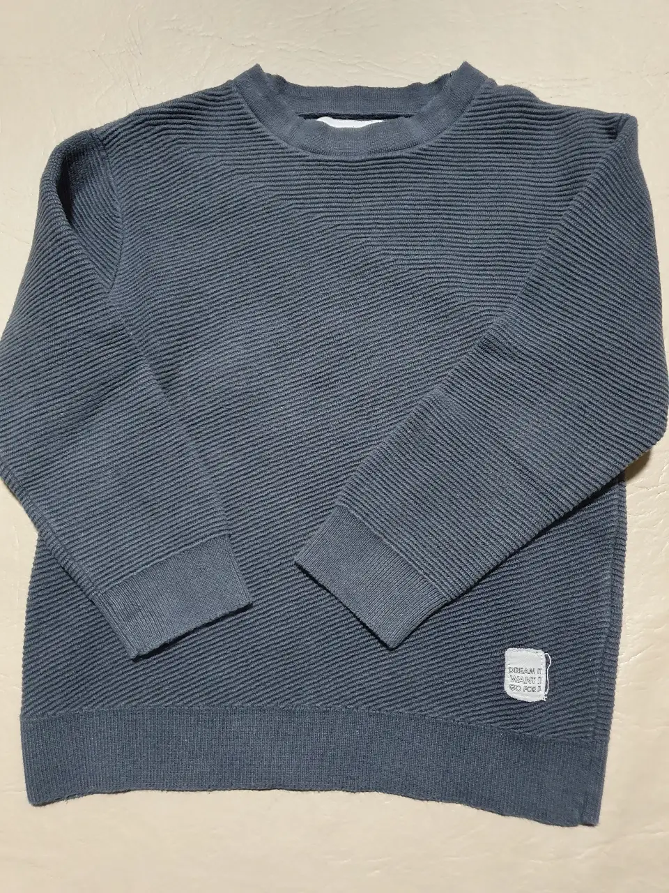 Sweater de tejido grueso color gris, con cuello redondo y mangas largas. Ideal para un look casual y abrigado.