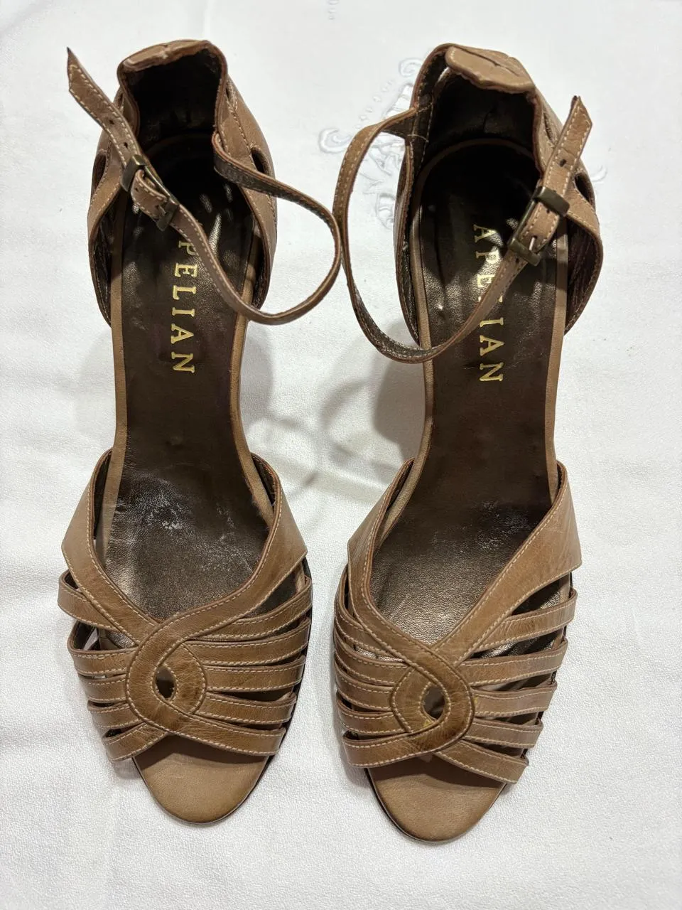 Sandalias de taco alto color marrón con detalles calados y pulsera en el tobillo. Ideales para un look elegante y sofisticado.