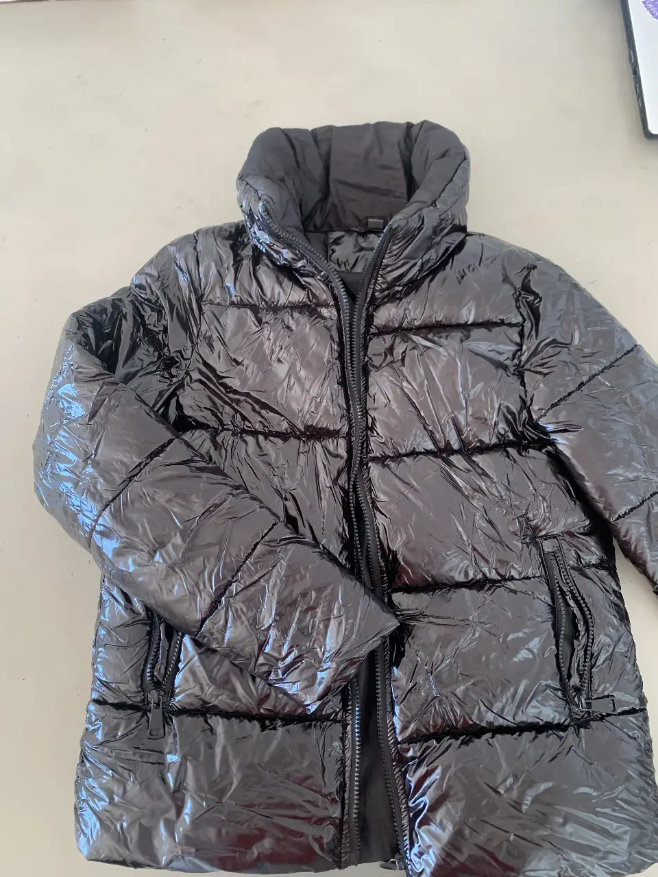 Campera inflable negra brillante, ideal para el invierno. Con cierre frontal y bolsillos, perfecta para un look casual y abrigado.