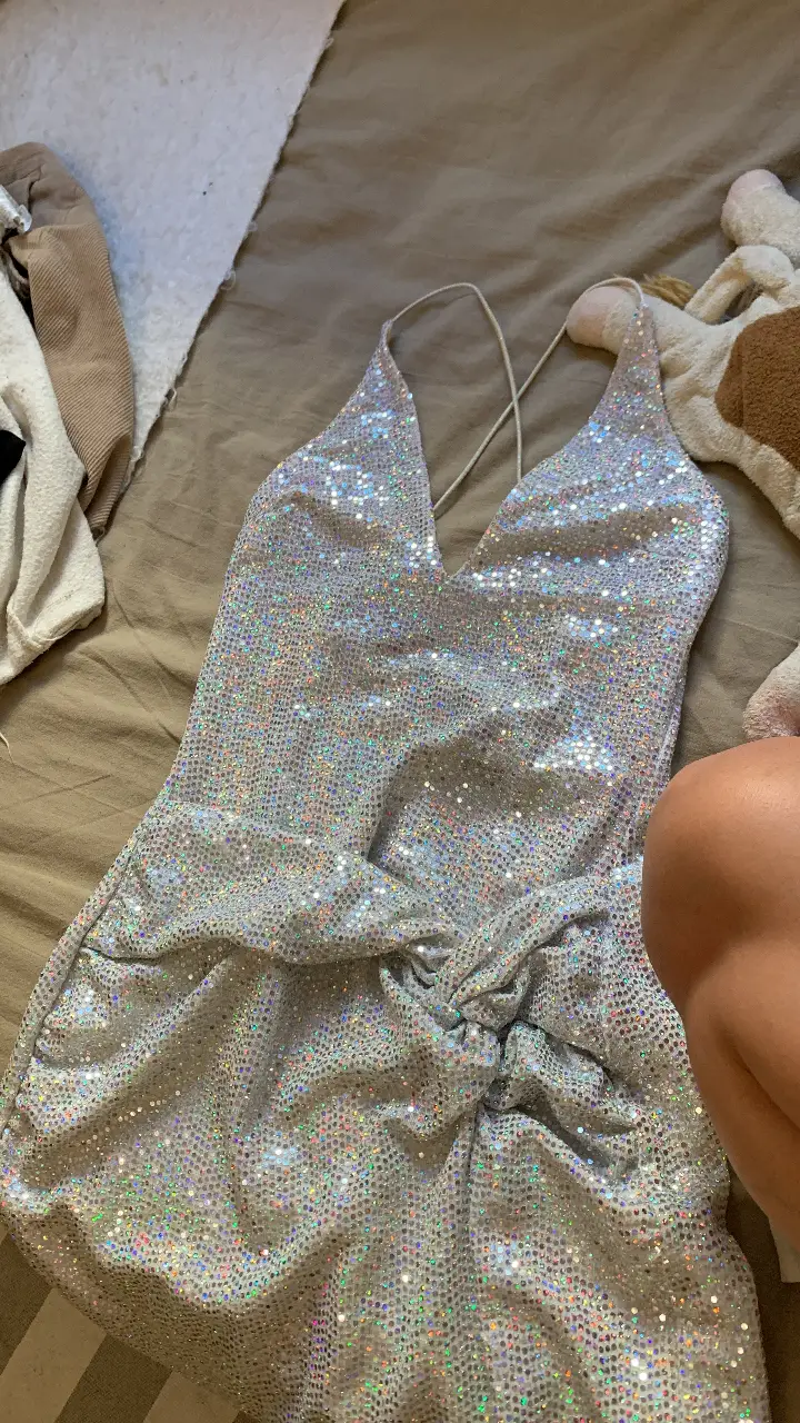 Vestido mini de fiesta plateado con lentejuelas. Ideal para eventos especiales y salidas nocturnas. Diseño ajustado con escote en V y espalda descubierta. Marca Bershka.