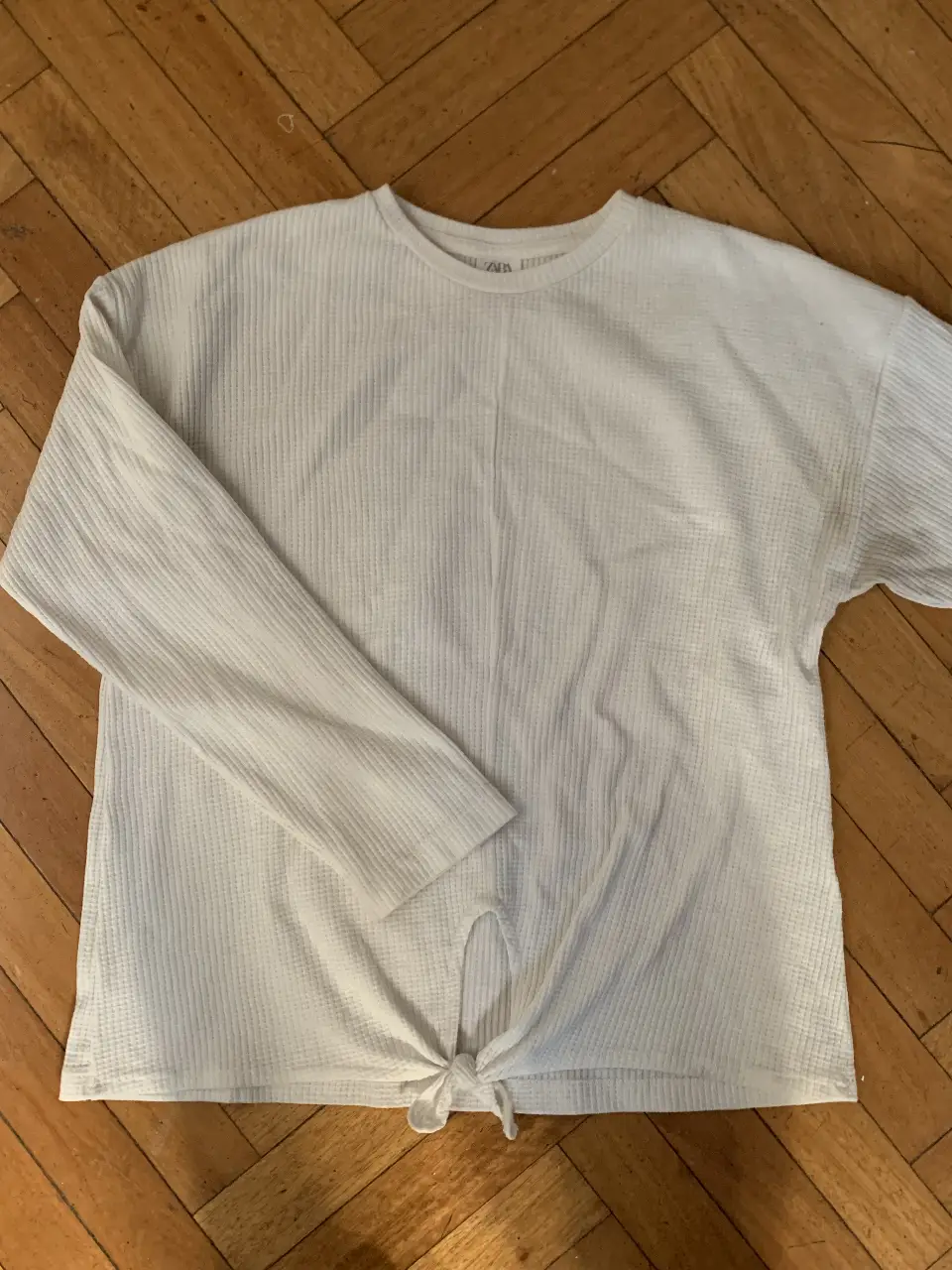 Remera manga larga de tejido waffle con detalle de lazo en la cintura. Ideal para un look casual y cómodo.