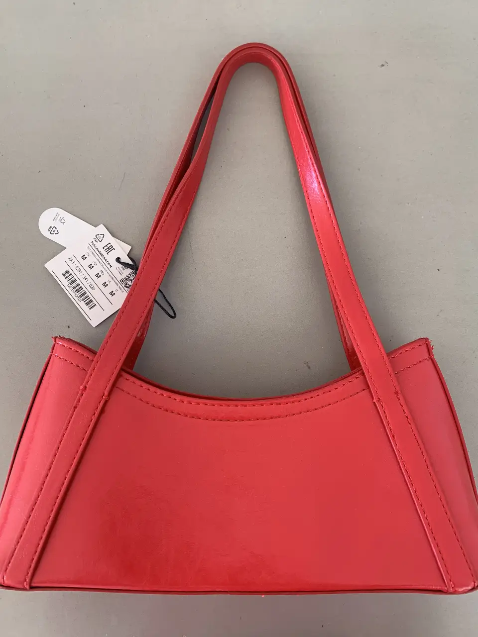 Cartera de hombro roja, estilo baguette, con manija superior. Ideal para un look moderno y elegante.