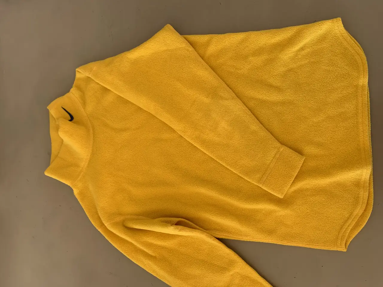 Buzo de cuello redondo amarillo de polar, con el logo de Nike en negro. Ideal para el invierno.