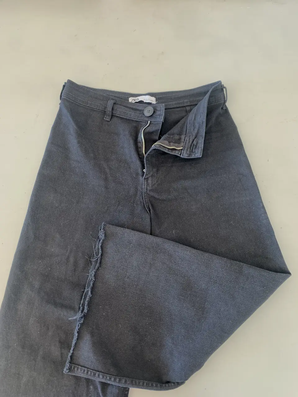 Pantalón suelto de jean negro, con corte recto y detalle de desflecado en el borde inferior. Ideal para un look casual y moderno.