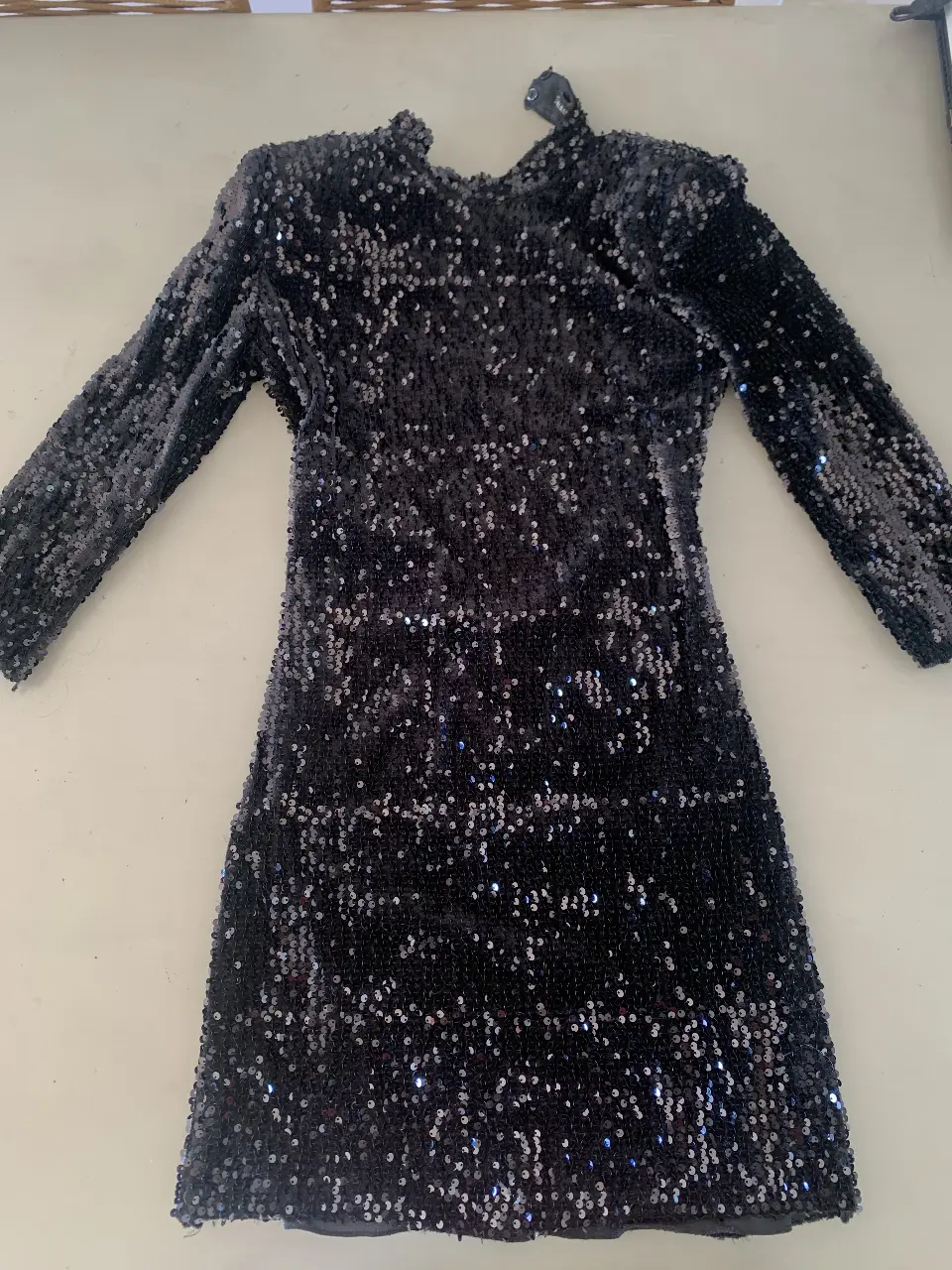 Vestido mini negro con lentejuelas, ideal para fiestas y eventos especiales. Diseño elegante y llamativo, perfecto para destacar en cualquier ocasión.