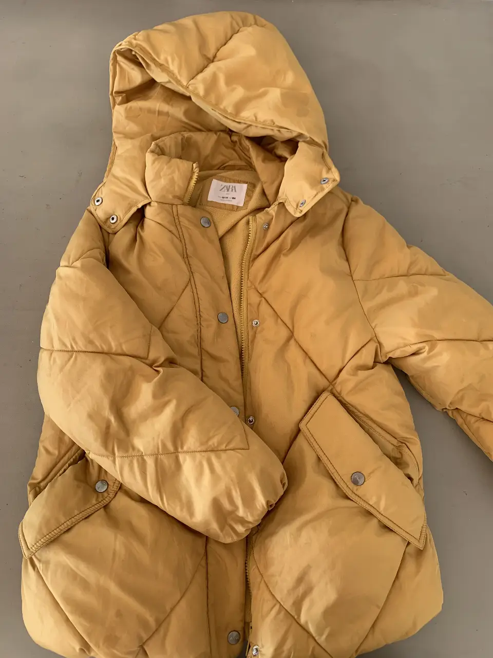 Campera puffer amarilla con capucha y bolsillos. Ideal para el invierno, cómoda y abrigada. Marca Zara.