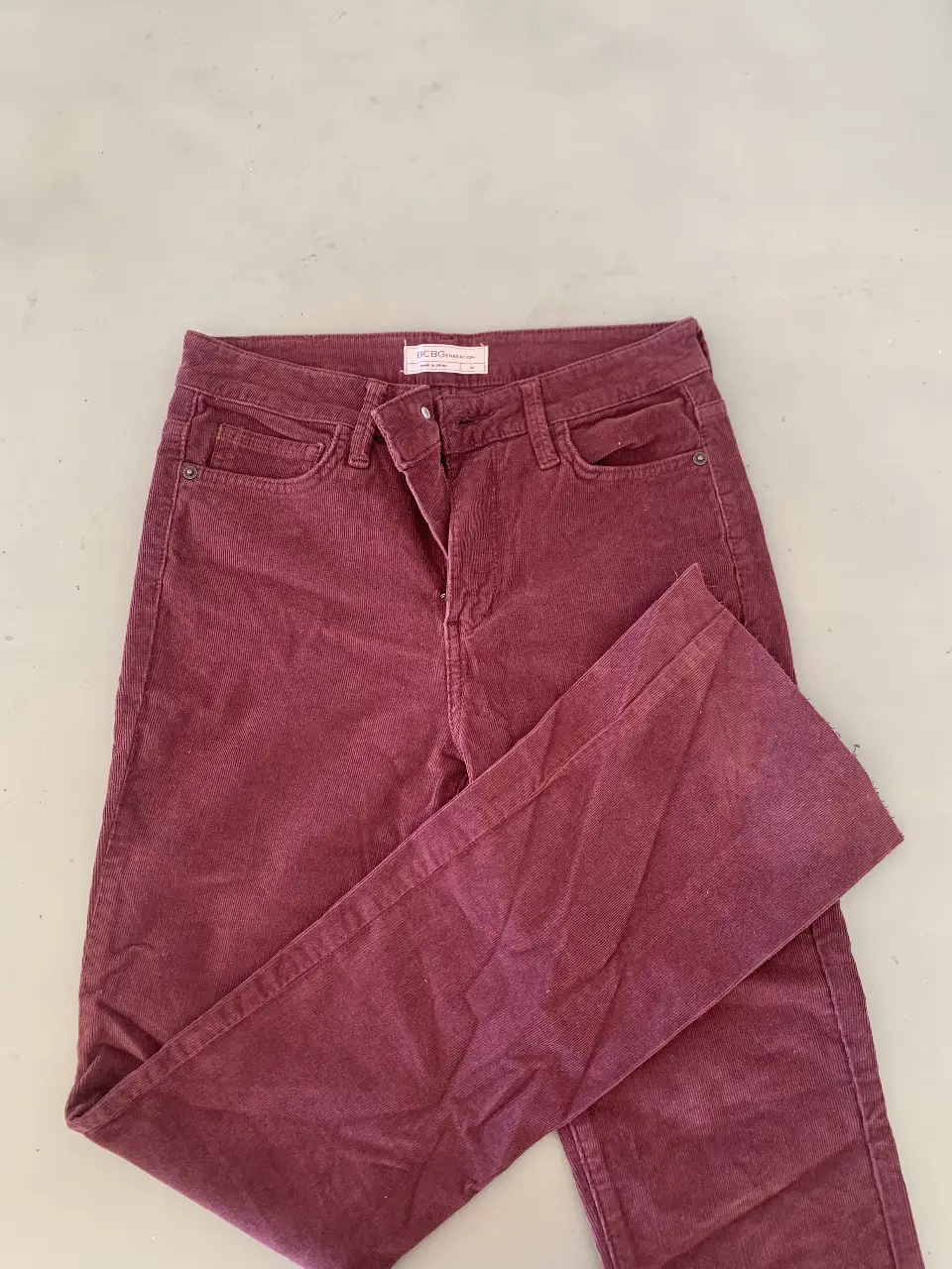 Pantalón de corderoy color borgoña, tiro medio, corte recto. Ideal para un look casual y cómodo.