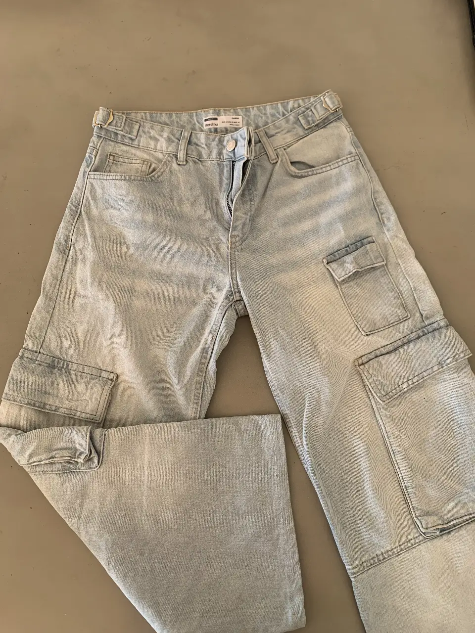 Pantalón cargo de jean celeste claro, tiro medio, con bolsillos laterales y detalles de diseño. Ideal para un look casual y moderno.