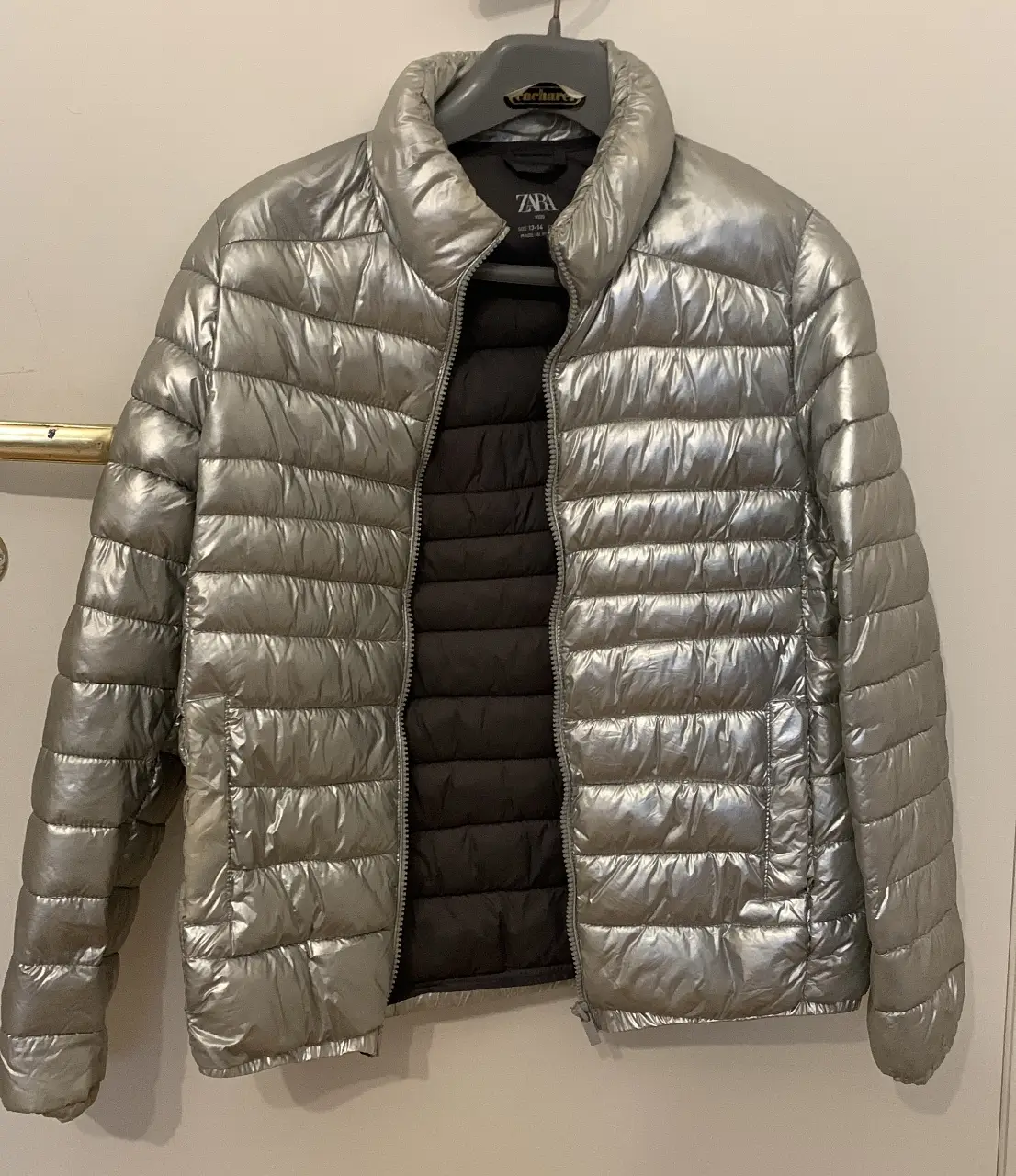 Campera de pluma plateada de la marca Zara, ideal para el invierno. Con cierre frontal y cuello alto. MUY abrigada