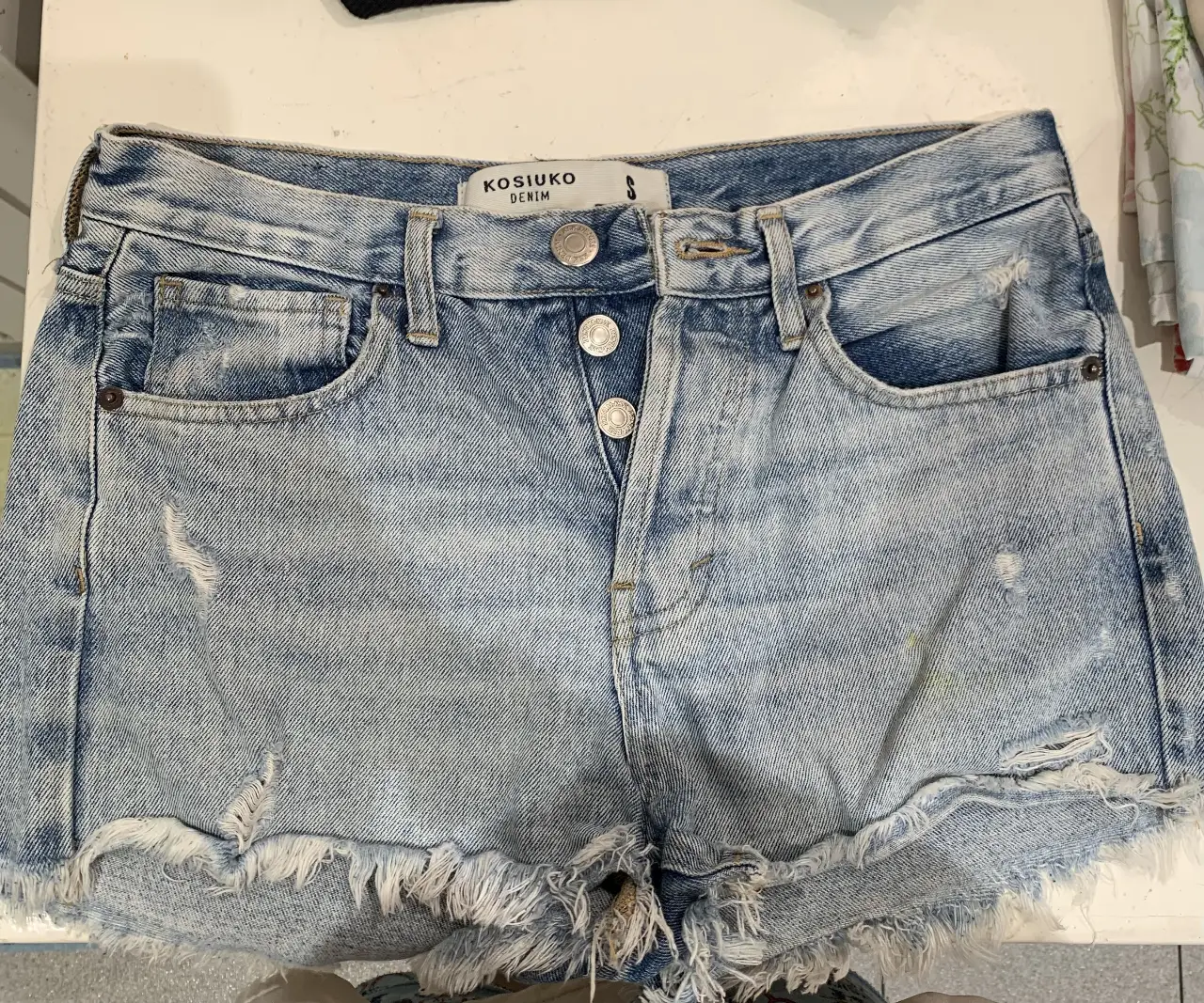 Short de jean de mujer, tiro medio, con detalles de roturas y desflecado en el borde. Ideal para un look casual y moderno. TALLE S
