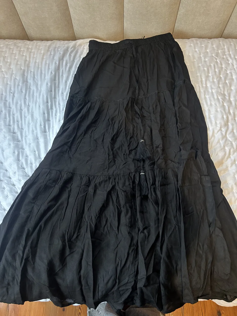 Pollera larga negra con tajos y detalles de bordado en la parte superior. Posee elástico en la cintura.