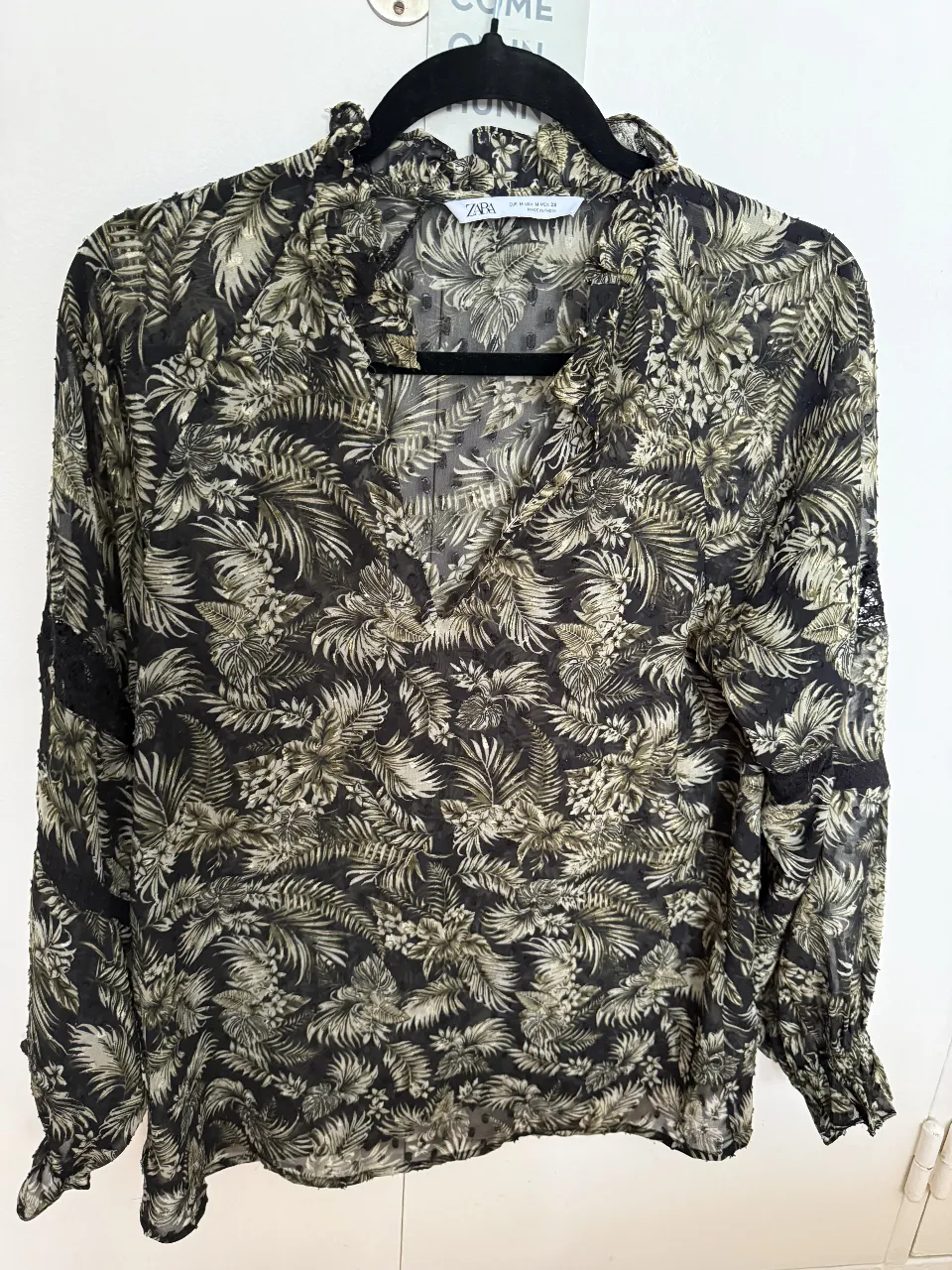 Blusa estampada con flores y hojas en tonos verdes y negros. Posee detalles de encaje en las mangas y cuello con volados y botoncito. Mangas largas con puño fruncido. Ideal para un look boho chic. La tela es plumeti, super delicada