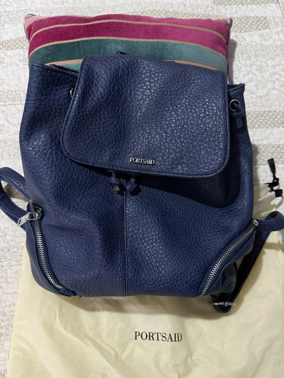 Mochila azul de cuero sintético con solapa y cierre. Ideal para uso diario. Practicamente nueva, va con la bolsa