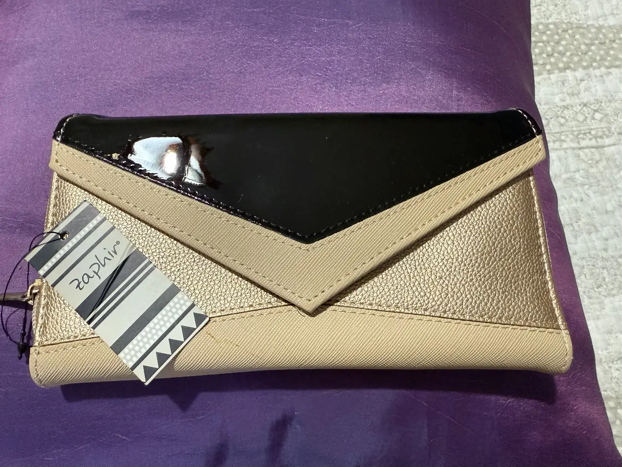 Cartera sobre de mujer, color dorado y negro, con solapa y cierre. Ideal para llevar tus esenciales con estilo.