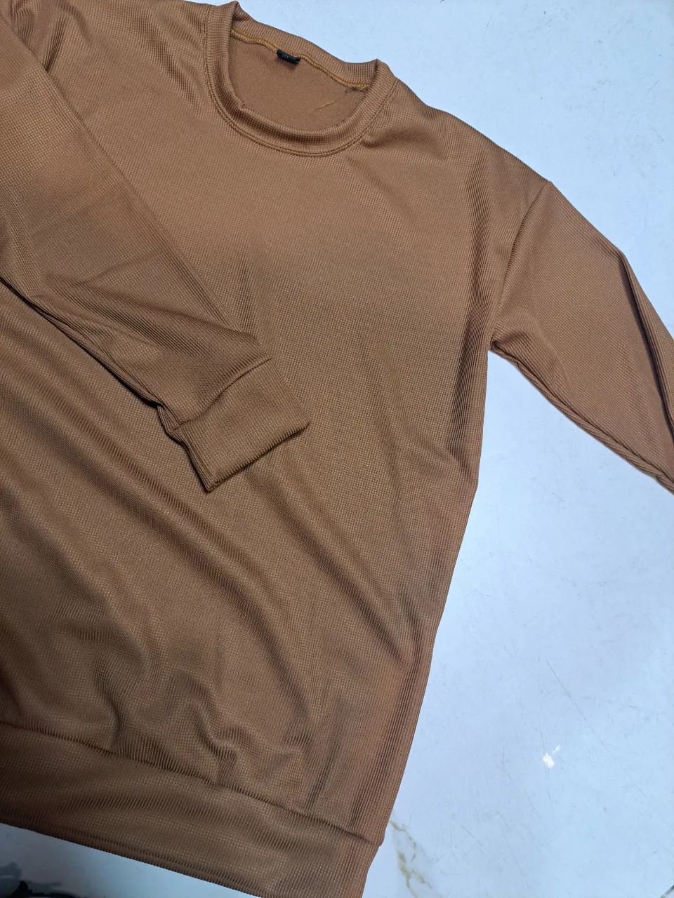 Buzo de cuello redondo en color marrón, ideal para un look casual y cómodo. Confeccionado en un tejido suave y con un diseño liso, este buzo es perfecto para el día a día.