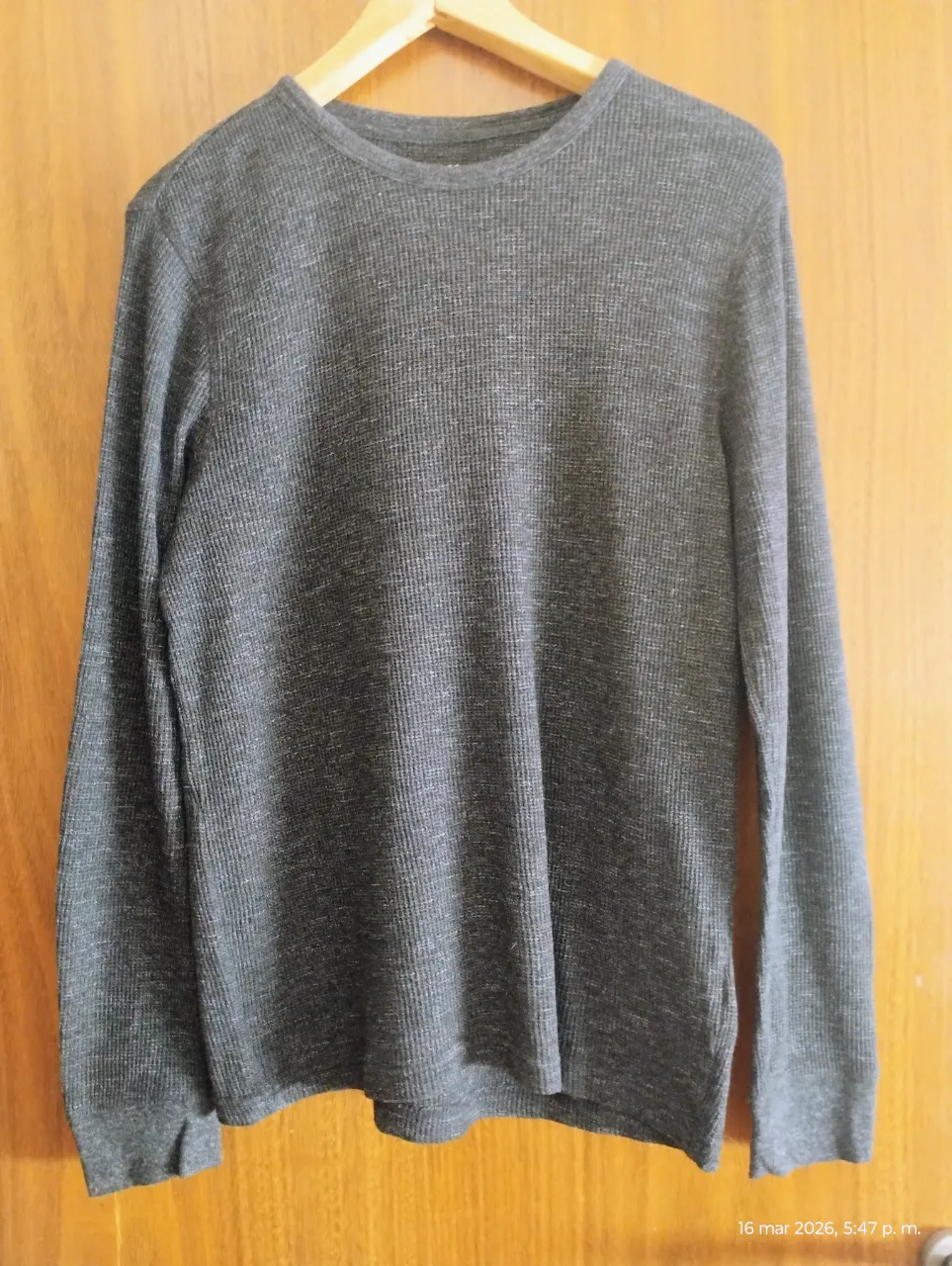 Remera gris de manga larga con cuello redondo. Tejido texturizado.