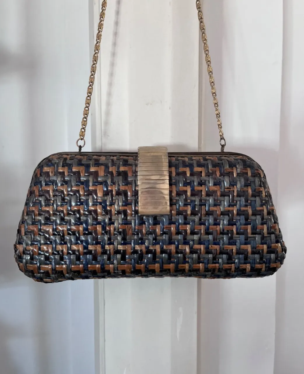 Cartera de mano tejida en tonos azules, marrones y crudos, con detalles metálicos dorados en el cierre y cadena. vintage. buen estado en general. usada. algo de desgaste en las partes metálicas. interior de gamuza. medidas 28 x 14 + 44 correa.