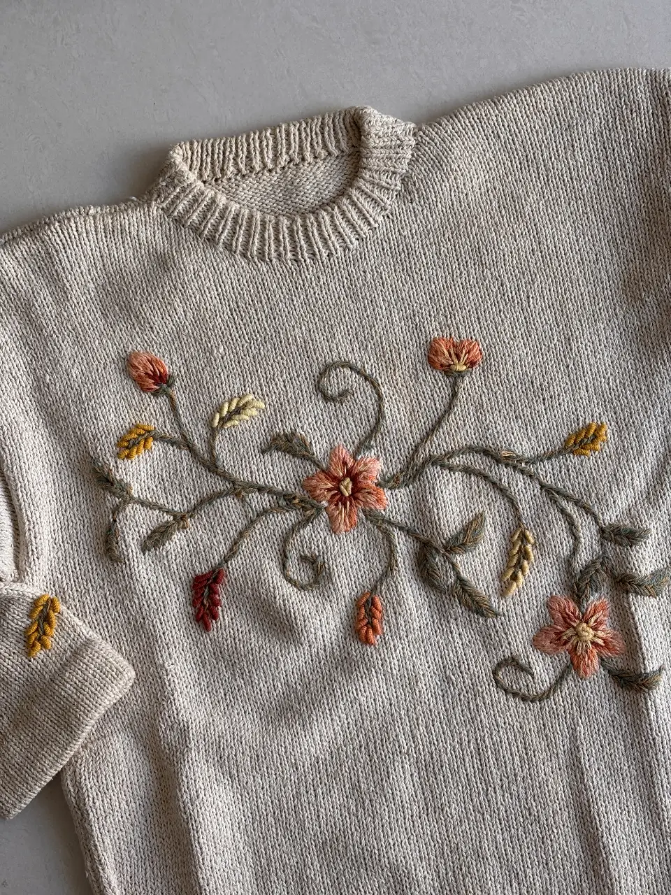 Sweater tejido a mano con bordado floral en tonos cálidos. Ideal para un look artesanal y cómodo.