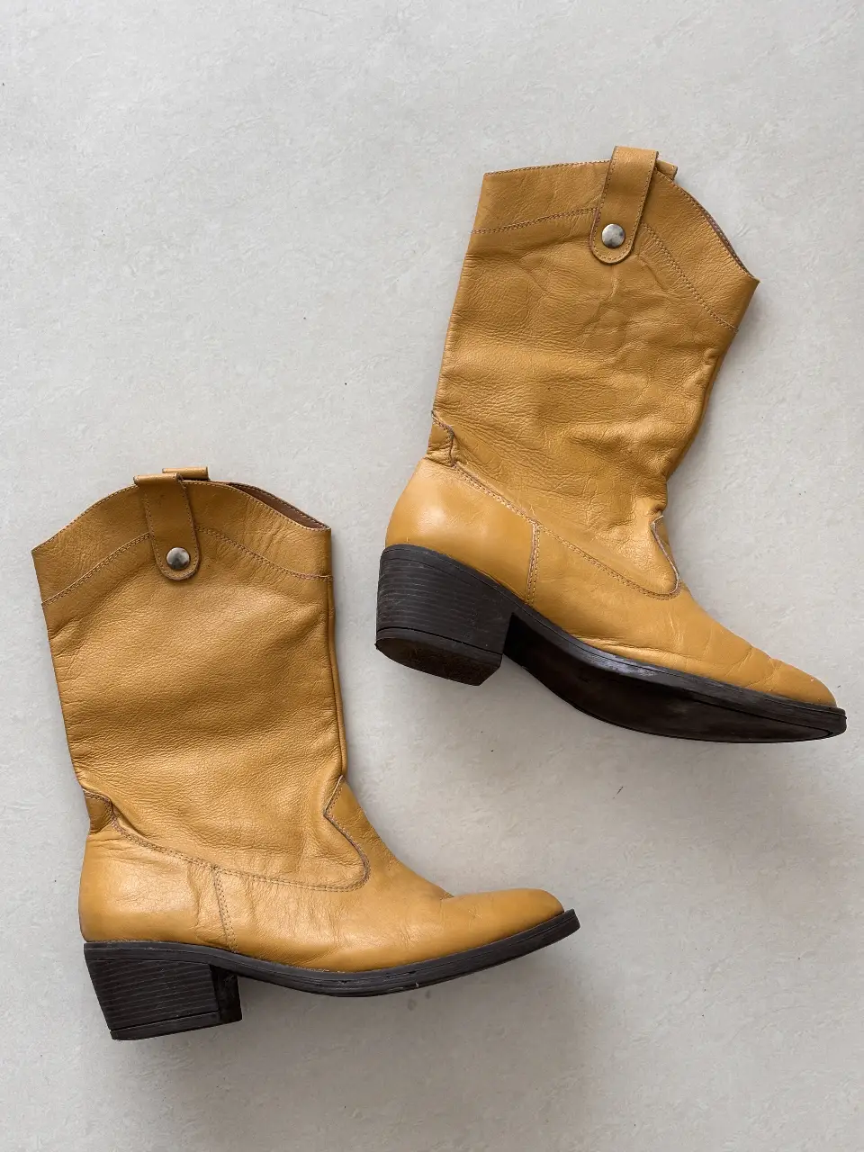 Botas de cuero vacuno color mostaza, estilo cowboy, con taco bajo y detalles de diseño. Ideales para un look casual y con onda.