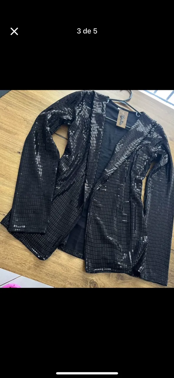 Blazer negro con lentejuelas, ideal para darle un toque de brillo a tus looks de noche o fiesta. Su diseño moderno y elegante lo convierte en un must-have.