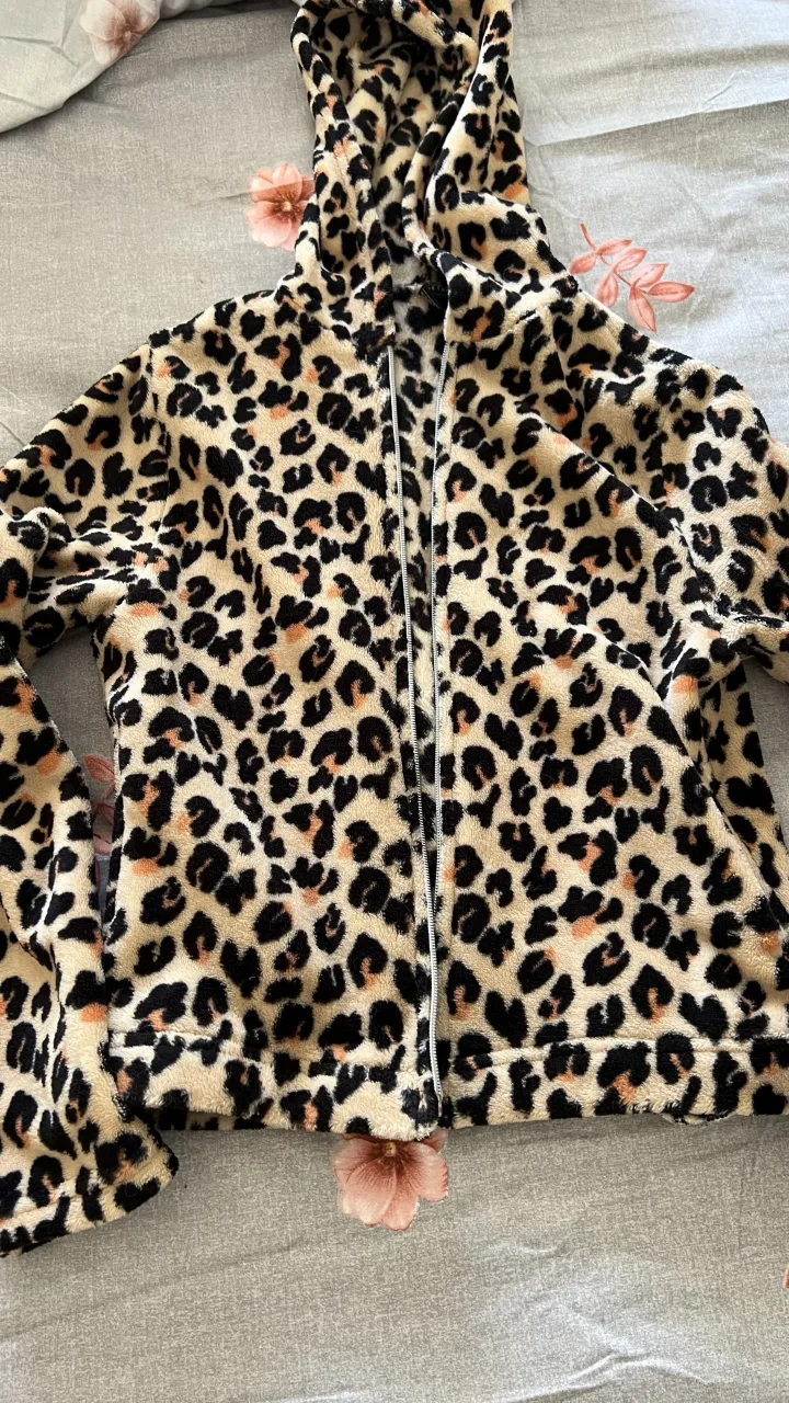 Abrigo súper suave con estampa de leopardo, ideal para estar cómoda en casa o para un look relajado. Tiene capucha y cierre al frente.