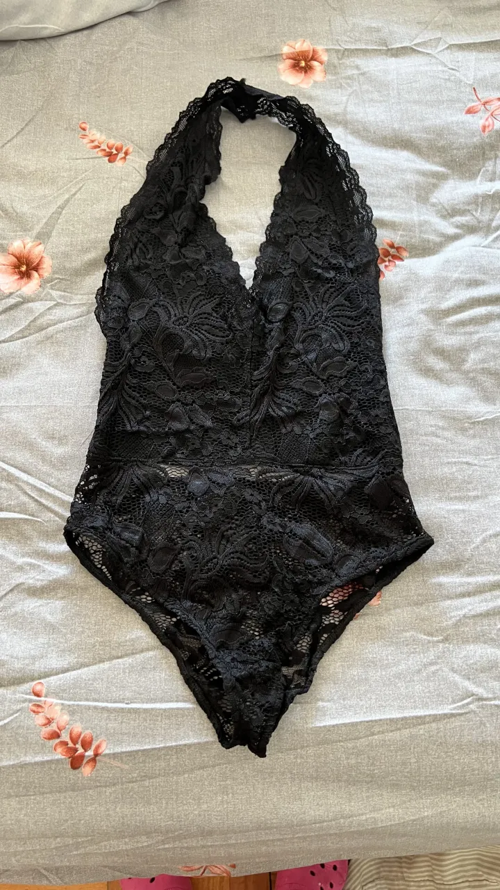 Body de encaje negro con escote halter y detalles de puntilla. Una prenda súper sensual y delicada, ideal para usar con un jean o pollera para un look nocturno o para sentirte especial en casa.