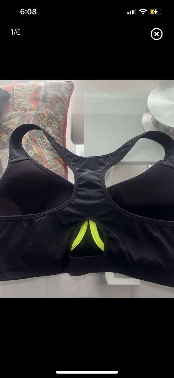 Top deportivo negro con diseño de espalda racerback y detalle en amarillo. Ideal para actividades de alto impacto.