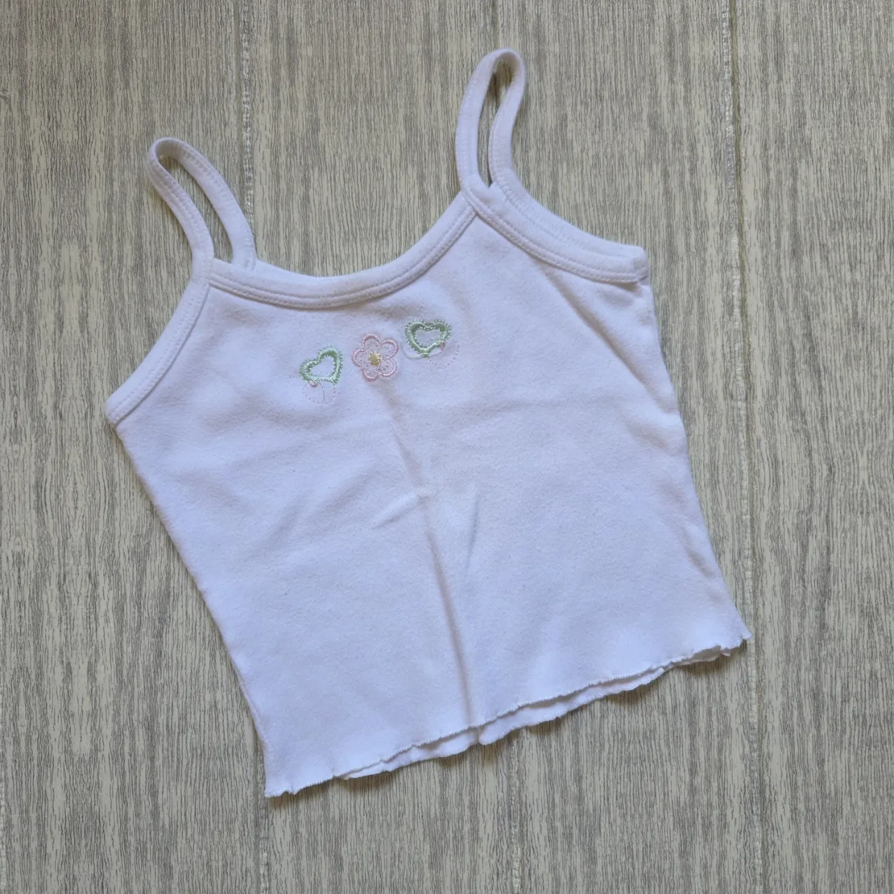 Musculosa blanca con bordado de flor y corazones en el frente.