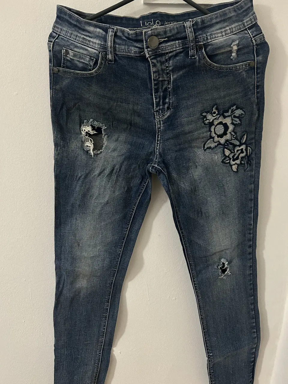 Jeans de mujer, tiro medio, con detalles de roturas y bordados florales. Un clásico renovado para un look canchero y con onda.