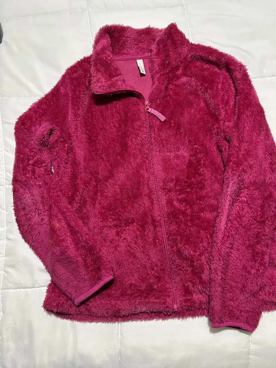 Buzo de polar rosa, con cierre frontal y cuello alto. Ideal para el invierno, cómodo y abrigado.