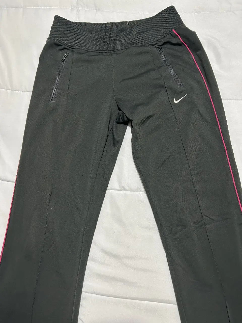 Pantalón deportivo negro de mujer con detalles en rosa y logo de Nike. Ideal para actividades físicas o uso casual. Talla XS 