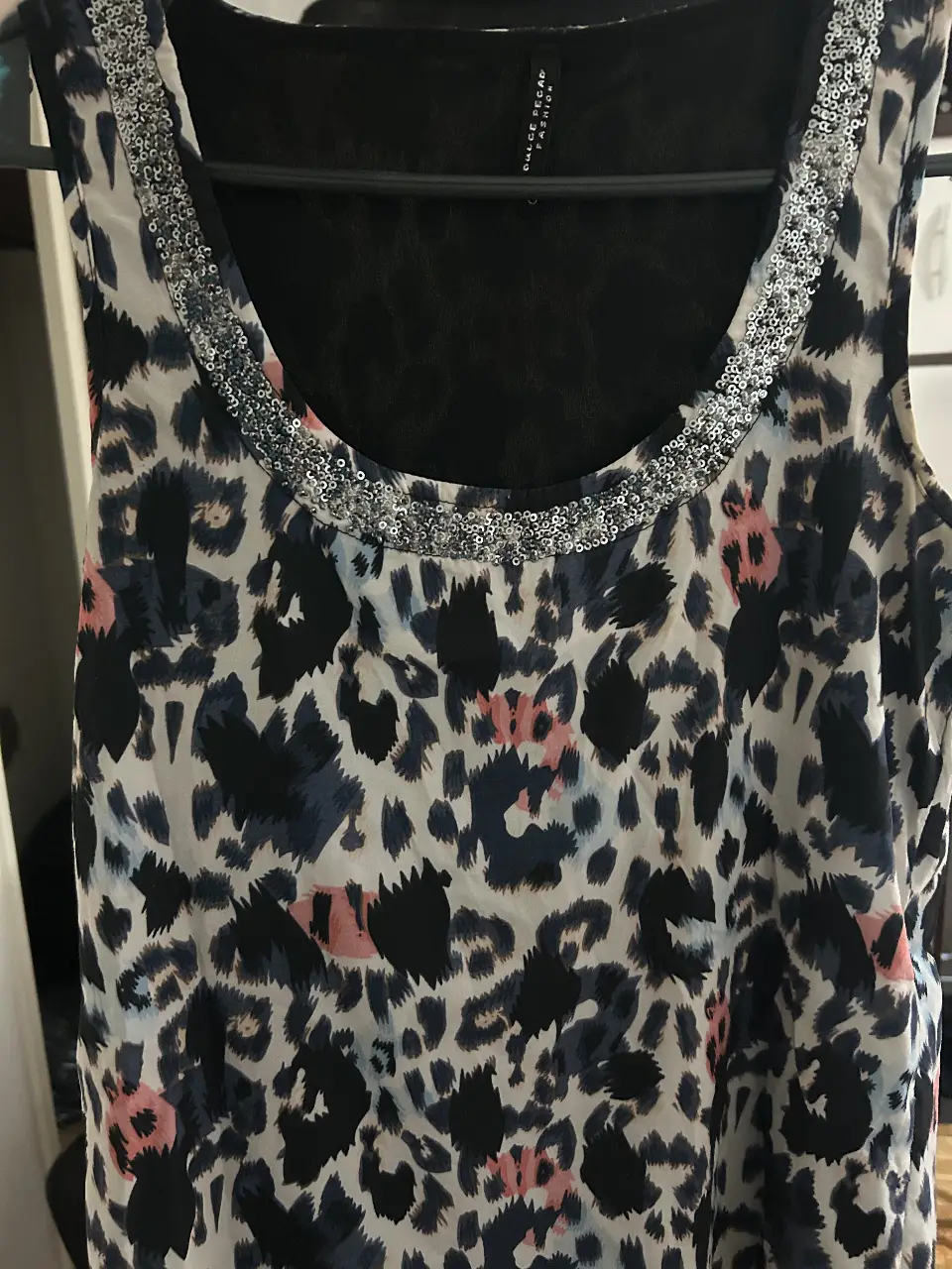 Musculosa con estampado de leopardo en tonos oscuros y detalles en rosa. Cuello redondo con apliques plateados. Ideal para un look casual y con estilo.