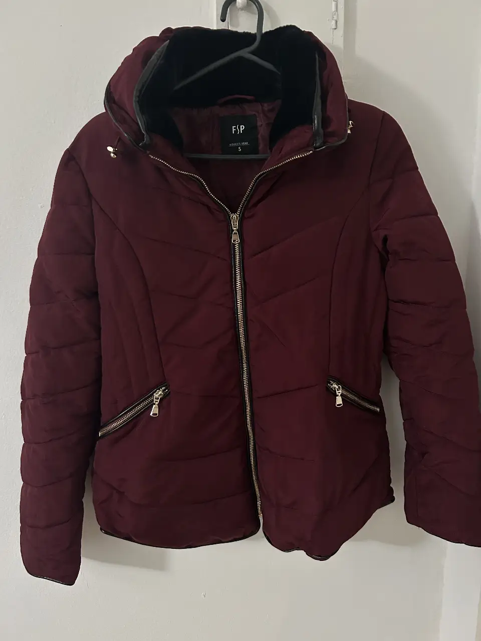 Campera rellena color bordó, con capucha y cierre frontal. Posee bolsillos con cierre y detalles en negro. Ideal para el invierno.