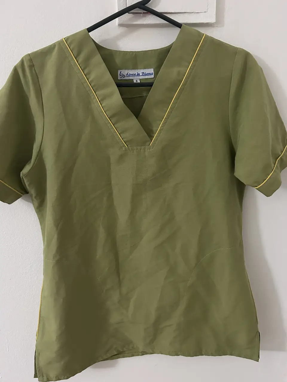 Conjunto de uniforme médico, incluye pantalón cargo verde con cintura elastizada y remera con cuello en V y detalles amarillos.