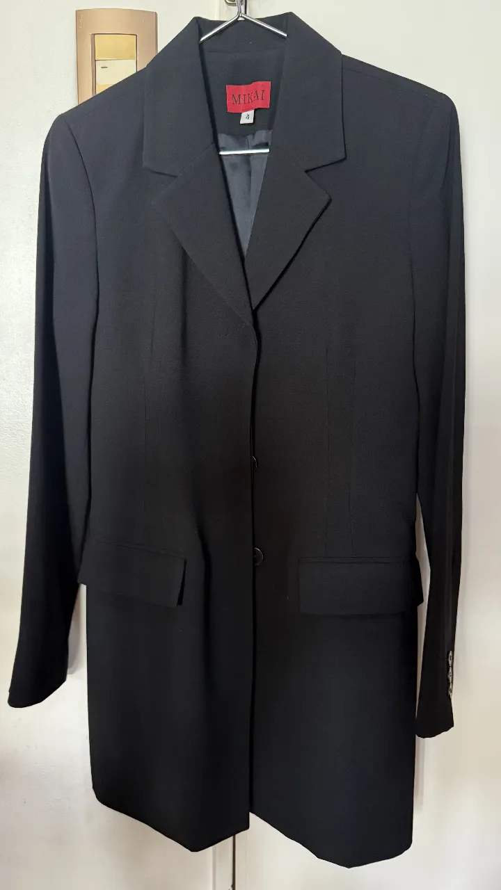 Elegante blazer negro de mujer, ideal para un look formal o de trabajo. Confeccionado en poliéster y acetato, este blazer de la marca Mikai presenta un diseño clásico con tres botones y bolsillos funcionales. Perfecto para combinar con pantalones sastreros o faldas.