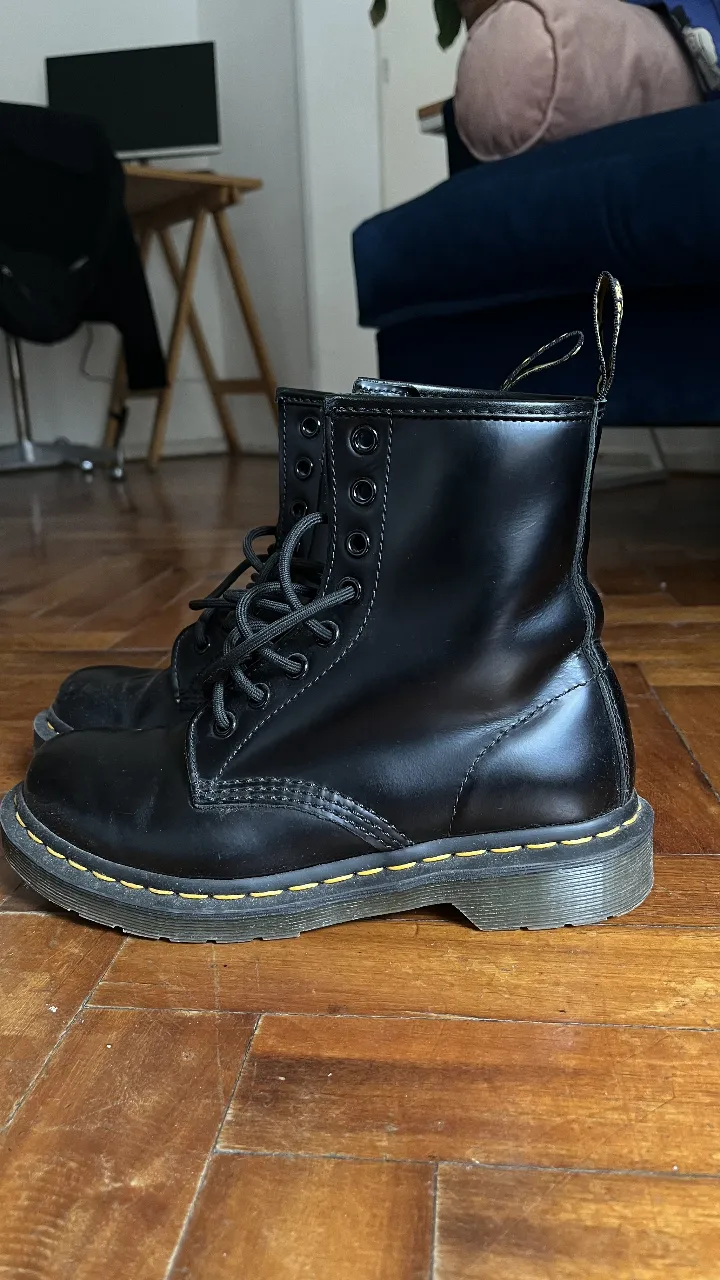 Borcegos Dr. Martens negros de cuero con plataforma, con costuras amarillas y suela resistente. Ideales para un look urbano y con estilo.